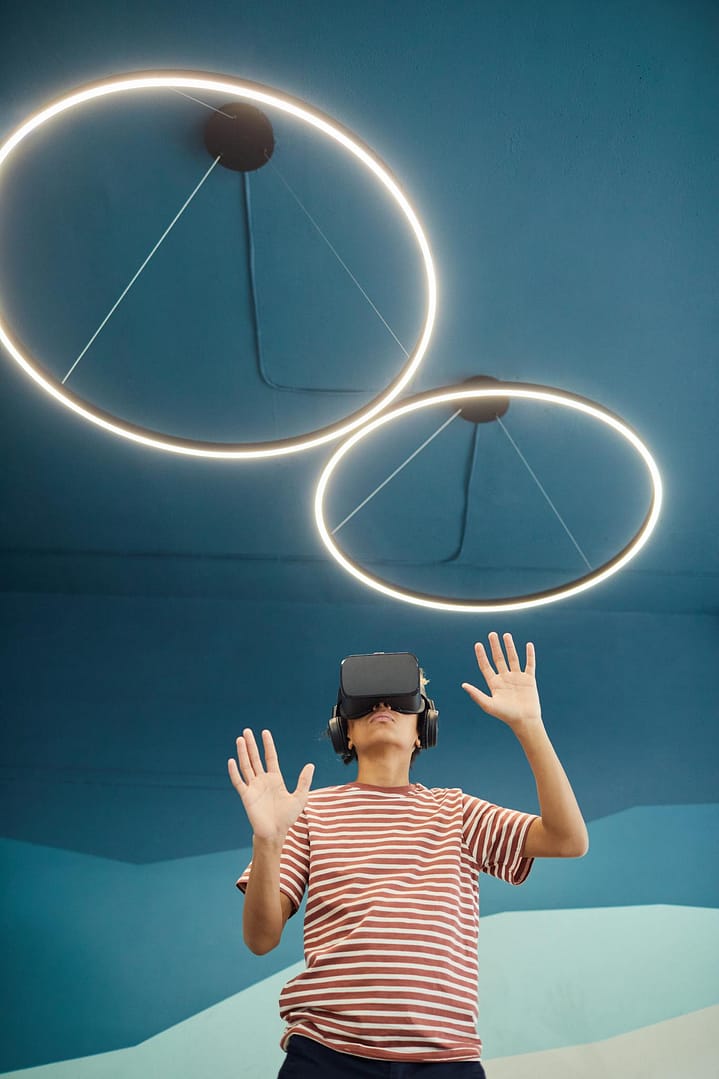 A young boy wearing VR headset interacting with virtual content in a modern room.